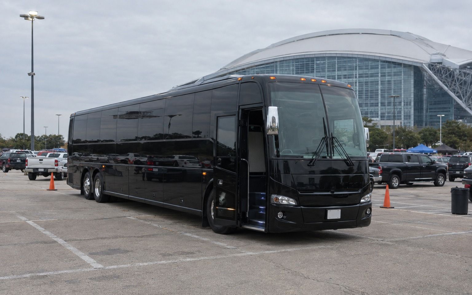 Black motor coach with its door open in the AT&T Stadium parking lot