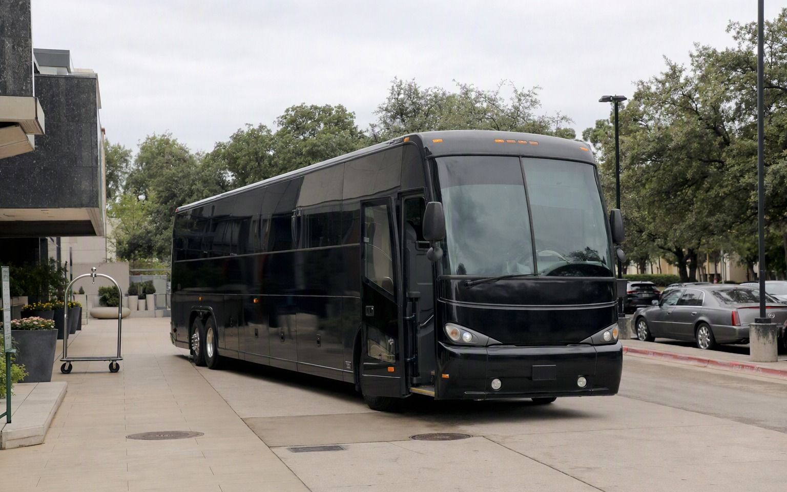 Black motor coach parked in the drive outside a hotel entrance