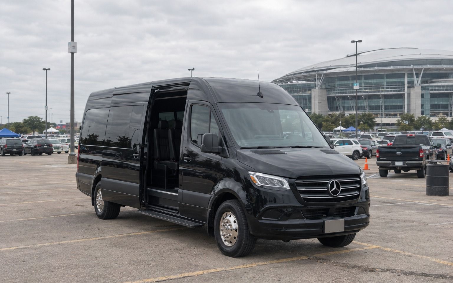 Black Sprinter van with its side door open in a stadium parking lot