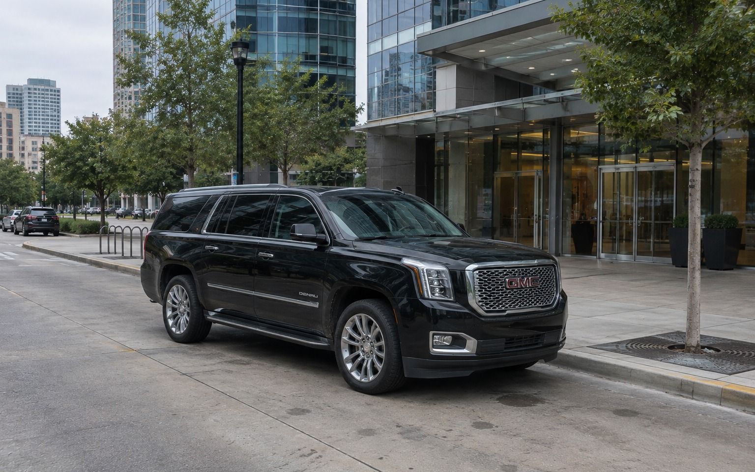 Black GMC Yukon parked outside the entrance of a glass office tower