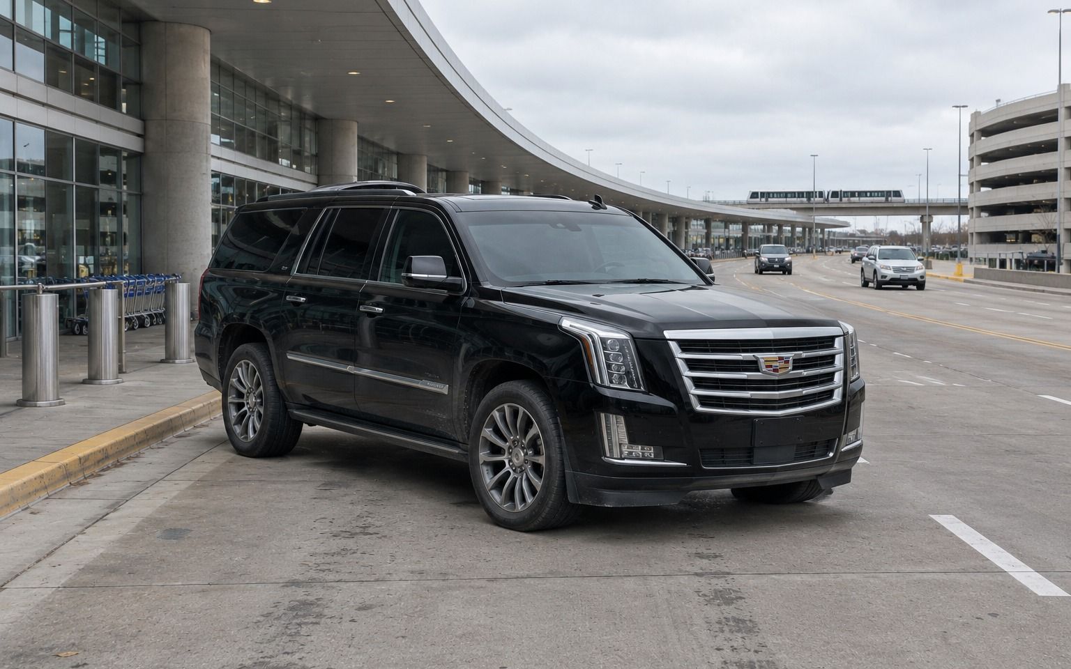 Black Cadillac Escalade waiting at the curb outside an airport terminal
