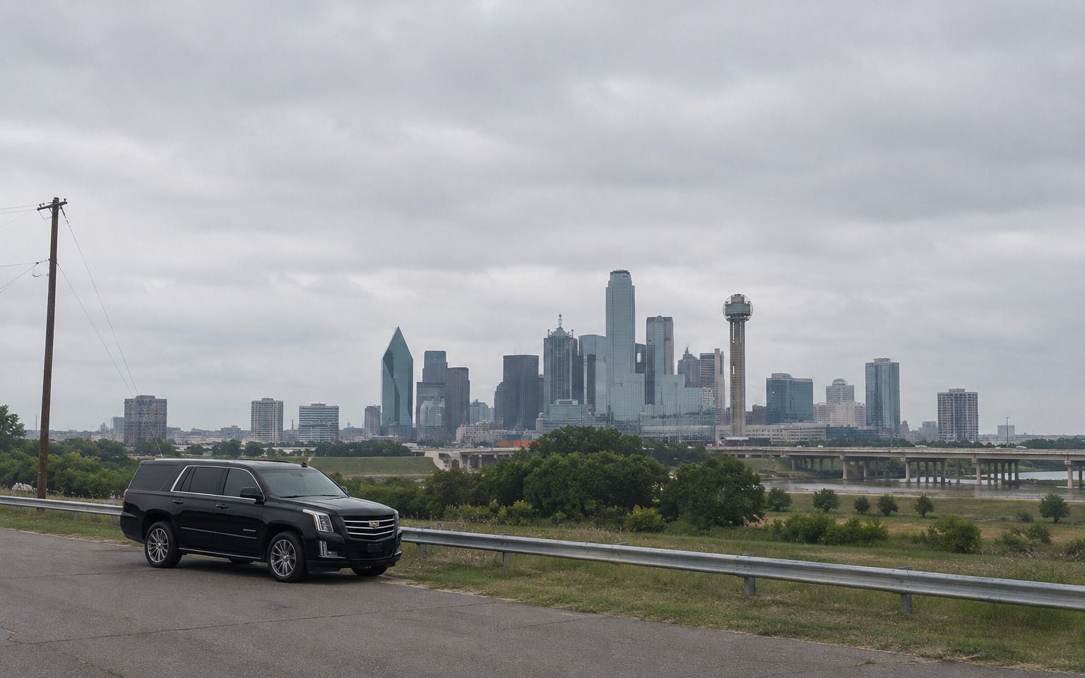 Black Cadillac Escalade parked on a roadside overlooking the Dallas skyline and Reunion Tower