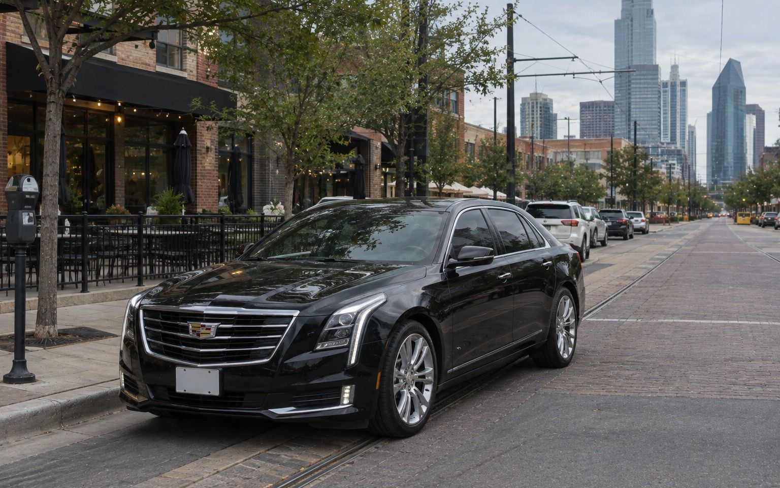 Black Cadillac sedan on a brick street with trolley tracks below the Dallas skyline