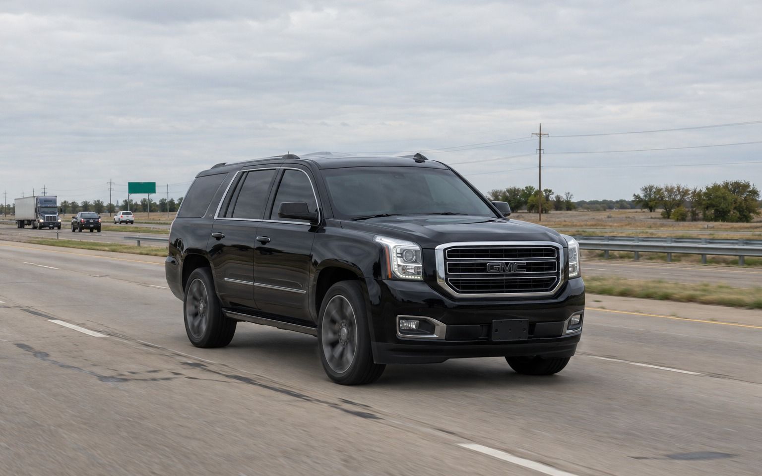 Black GMC Yukon driving down an open highway on a cloudy day