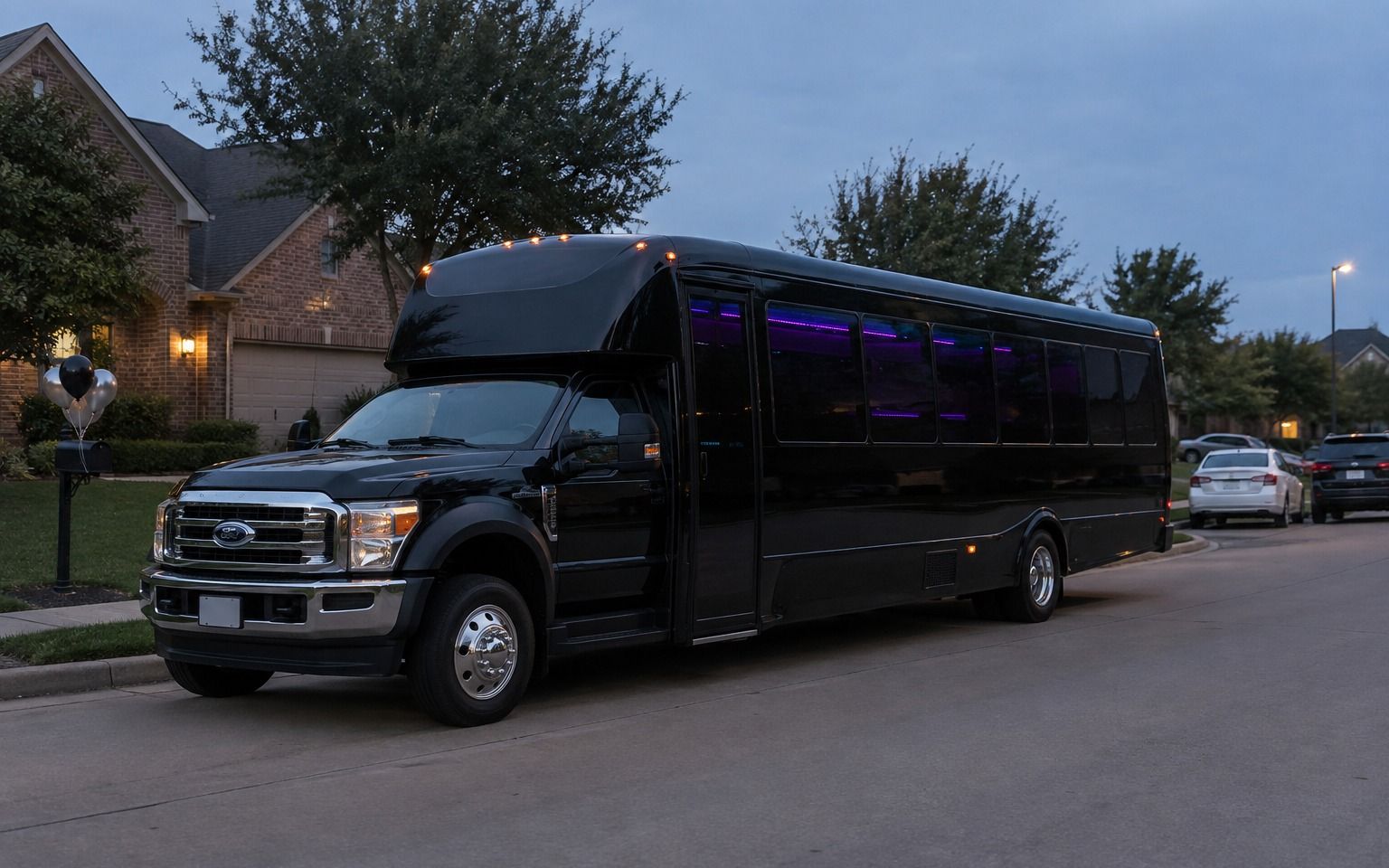 Black party bus with purple lights parked on a neighborhood street at dusk