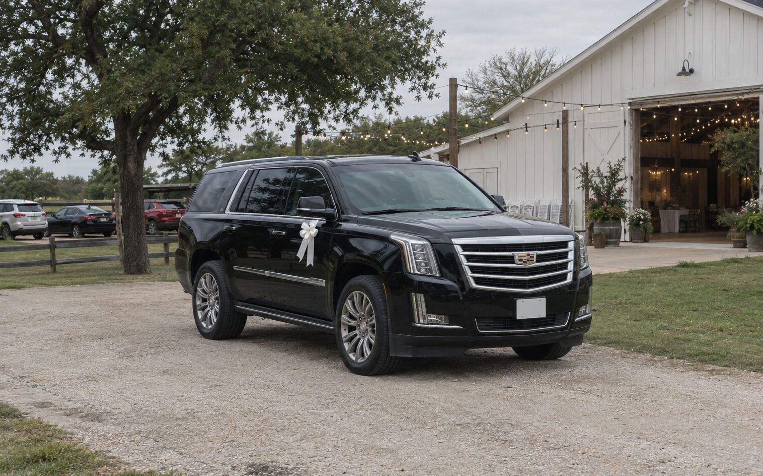Black Cadillac Escalade with a white bow parked outside a rustic barn venue