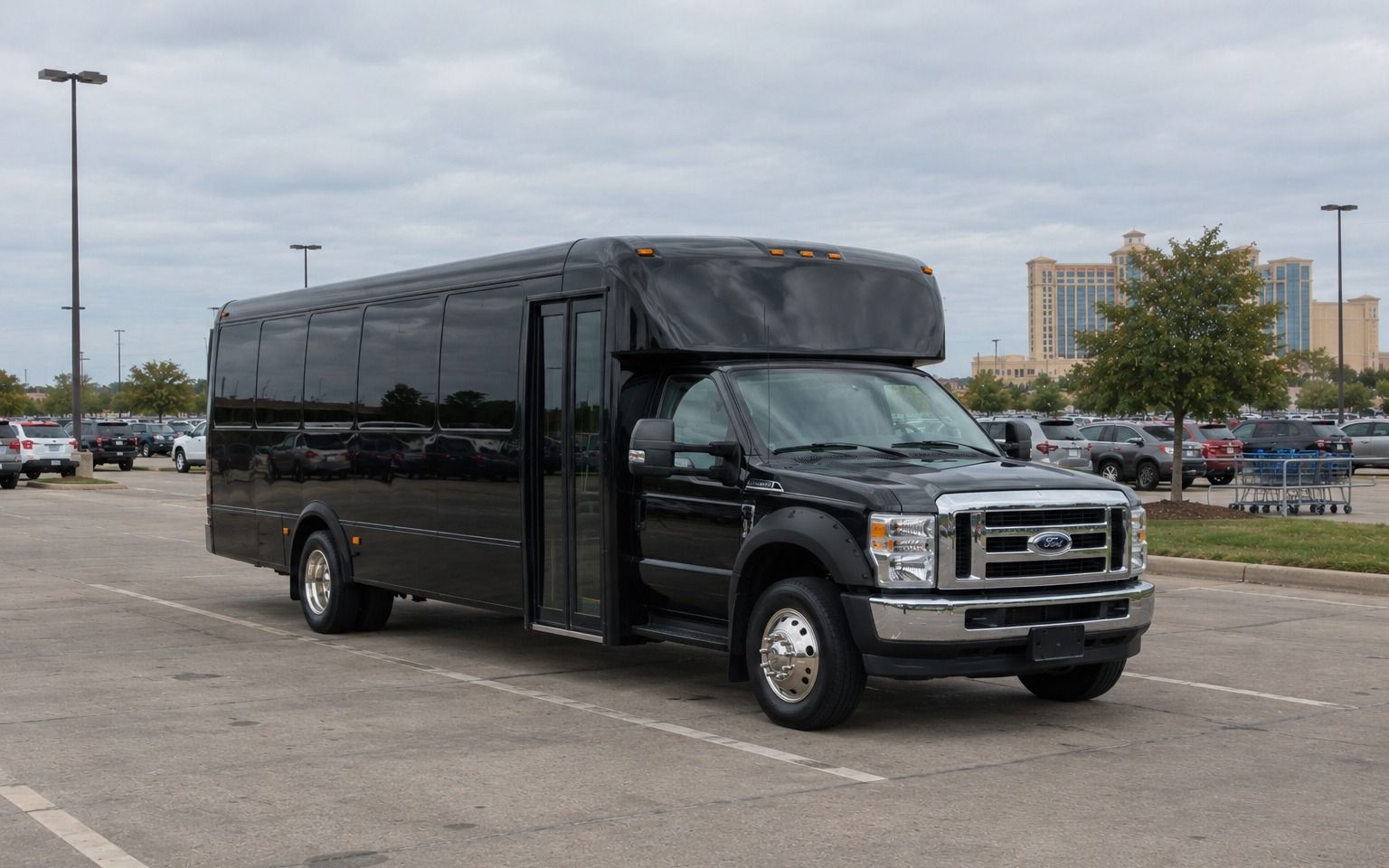 Black shuttle bus parked in a large lot near a tall resort hotel